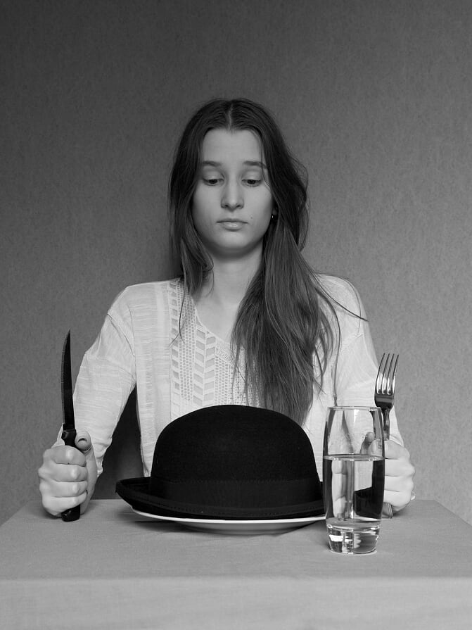 Photographie d'une jeune femme regardant son chapeau dans une assiette
