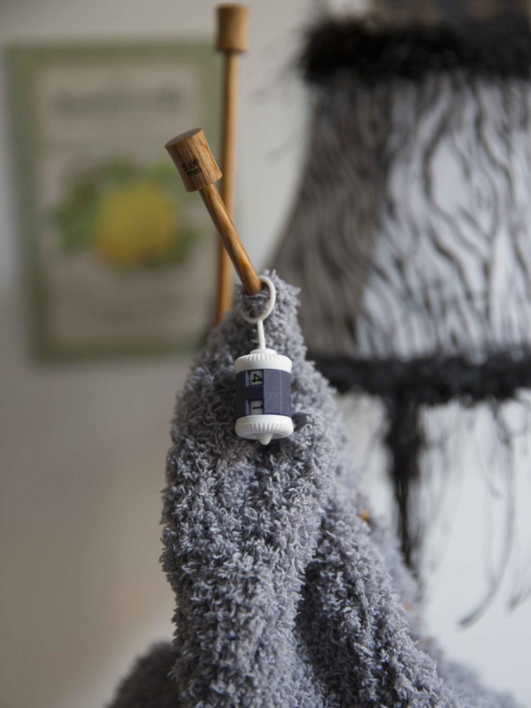 Photographie d'une paire d'aiguilles avec un tricot gris et un compte rang